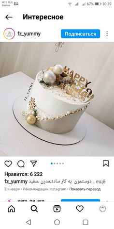 a white cake with gold lettering and decorations on it's side, sitting on top of a table