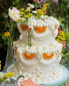 a three tiered cake with orange slices and flowers on the top is decorated in white icing