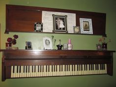 an old piano with pictures on it and other items sitting on the shelf above it