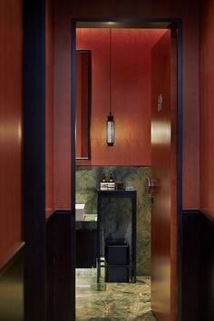 an open door leading to a bathroom with marble flooring and red wall coverings