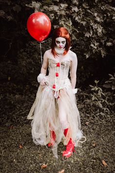 a woman dressed as a clown holding a red balloon