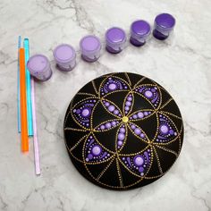 a black and purple circular object with candles next to it on a marble counter top