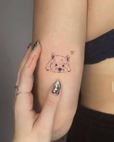 a woman's arm with a small tattoo of a dog on the left side