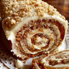 a cinnamon roll on a white plate with icing and crumbled toppings