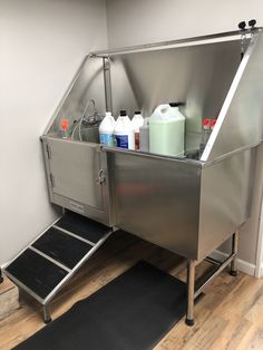 a stainless steel sink with several bottles and containers on the bottom, in a room