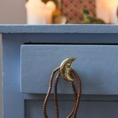 a close up of a drawer with beads on the handle and a candle in the background