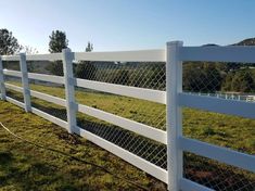 a white picket fence in the middle of a grassy field