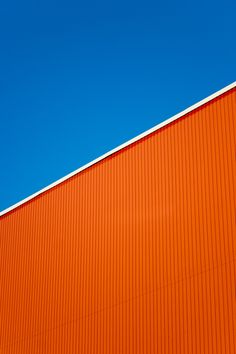 an airplane is flying in the blue sky over a building with orange walls and red trim