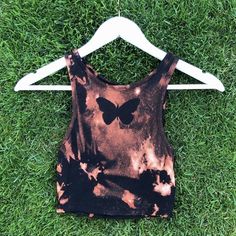 a black and brown tie dye shirt with a butterfly print on it sitting in the grass