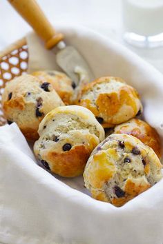 blueberry muffins in a basket with a glass of milk on the side