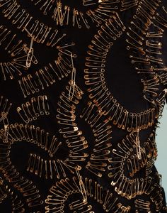 the back of a black dress with gold threadwork on it's neck and shoulders