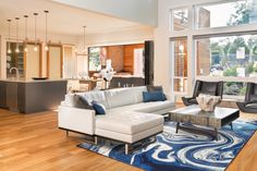 a living room filled with furniture and lots of windows next to a wooden flooring area