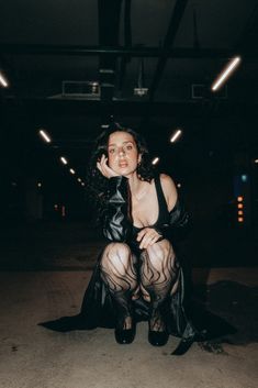 a woman sitting on the ground with her legs crossed wearing fishnet stockings and high heels