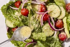 a salad with cucumbers, tomatoes and onions in it on a white plate