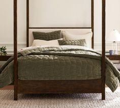 a bed with green bedspread and white pillows