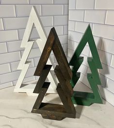 three wooden christmas trees sitting next to each other on top of a white tile counter