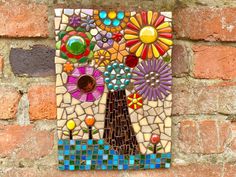 a mosaic art piece on a brick wall with flowers in the center and an image of a tree