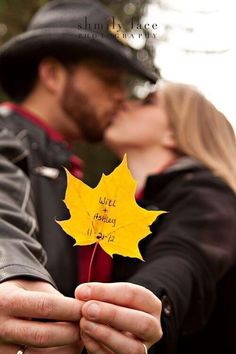 a man and woman kissing while holding a yellow leaf