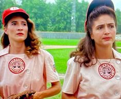 two women in baseball uniforms standing next to each other