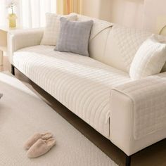 a living room with a white couch and pillows on the floor next to a window