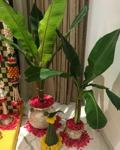 two potted plants sit on top of a table with flowers and other decorations around them