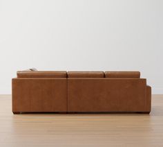 a brown couch sitting on top of a hard wood floor next to a white wall