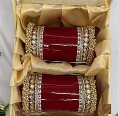 two red and gold bangles are sitting in a box with some ribbon on it