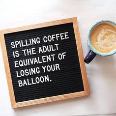 a cup of coffee next to a sign that says spelling coffee is the adult equivalent of losing your balloon