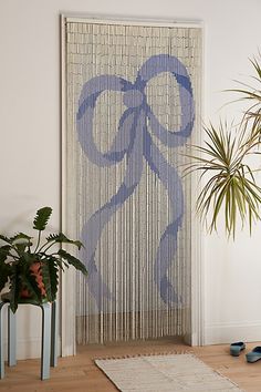 a living room with a rug, potted plant and curtain on the wall in front of it