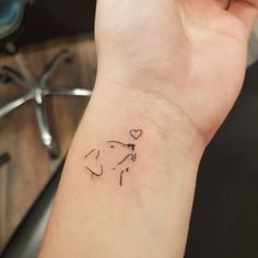 a small wrist tattoo with a dog's head and heart on the left side