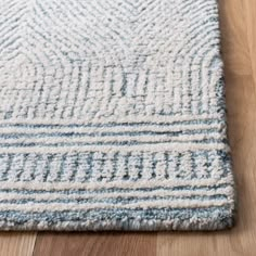 a blue and white rug on the floor with wood floors in the background at home