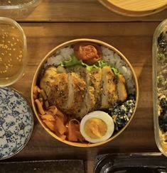 a bowl filled with rice, meat and vegetables next to two bowls full of soup