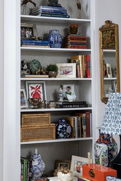 a bookshelf filled with lots of books and vases on top of it