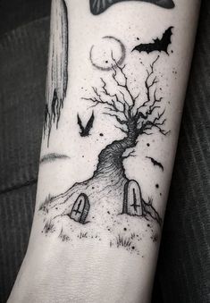 a black and white photo of a tree with bats on it's arm, next to a house