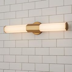 a bathroom light that is on the side of a wall with white bricks behind it