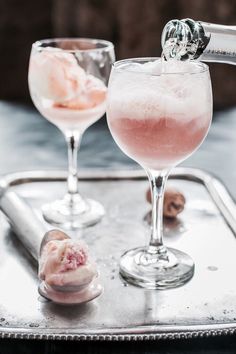 two wine glasses filled with ice cream on top of a metal tray next to each other