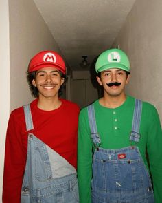 two men in overalls and hats standing next to each other with fake moustaches on their faces