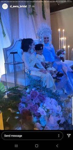 two women sitting on a couch with flowers and candles in the background at a wedding