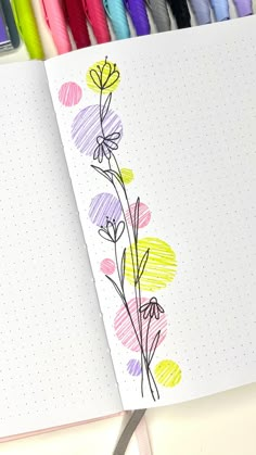 an open notebook with flowers drawn on it and colored crayons in the background