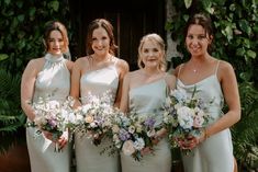 the bridesmaids are all dressed in white dresses and holding their bouquets together