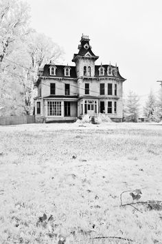 black and white photograph of an old house in the winter with snow on the ground