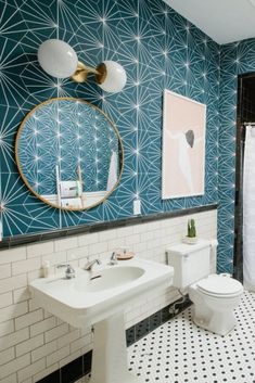 a white toilet sitting next to a sink in a bathroom under a painting on the wall