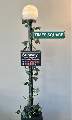 there is a street sign that says times square and subway in front of a plant