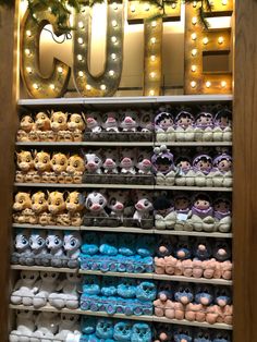 a display case filled with lots of different types of stuffed animals in front of a lighted sign