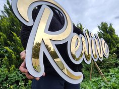 a person holding up a sign that says relive in front of some bushes