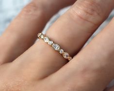 a woman's hand with a diamond ring on top of her finger and the other hand holding it