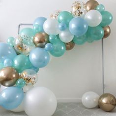 a bunch of balloons that are in the shape of a arch with gold, white and blue balloons