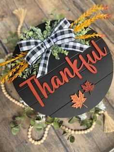 a wooden sign that says, thank you with fall leaves and greenery around it