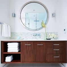 a bathroom with a sink, mirror and wooden cabinetry in it's center