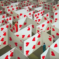 two people are standing in the middle of a maze with red hearts on white walls